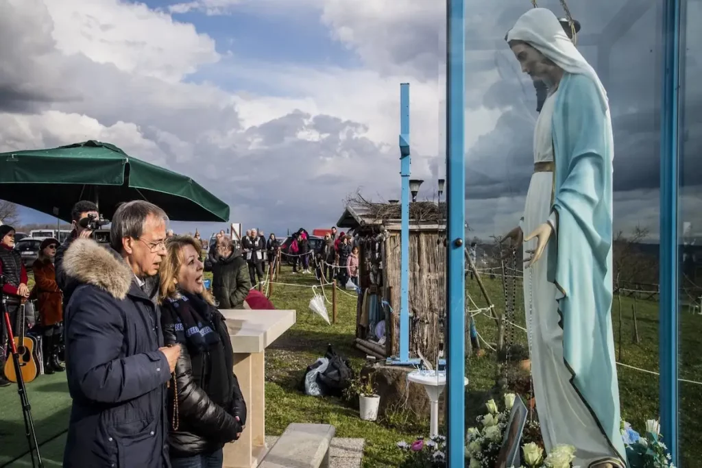 Fedeli pregano davanti alla statua della Madonna